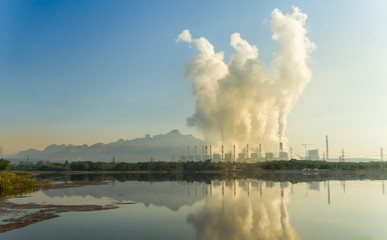 Hot steam from chimney at coal power plants against blue sky.