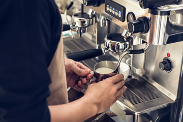 Barista steaming milk with coffee machine