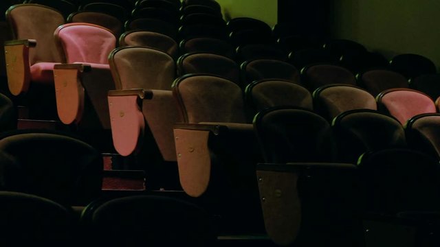 Back of conductor and musicians in concert hall and banister.