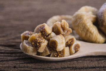 portion cut dried figs on wooden spoon and on wooden table