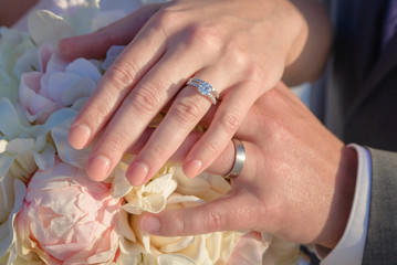 Bride and Groom holding hands over Bouquet at their Wedding