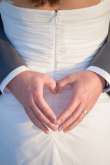 Groom Holding His Hands in the Shape of a Heart on the back of his Bride's Wedding Dress