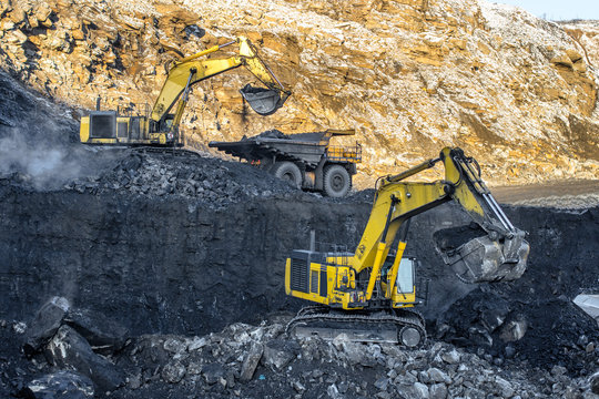 Big yellow dump truck and excavator in coal mine 

