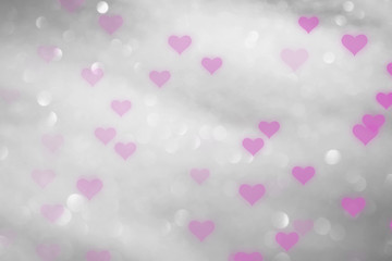Pink colored hearts on blurry silver bokeh background.