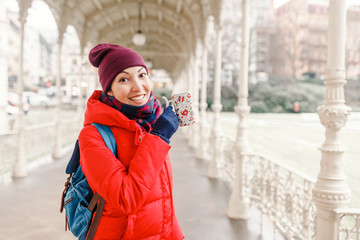 Happy woman drinks water from a hot thermal spring in Karlovy Vary, Czech Republic at winter time