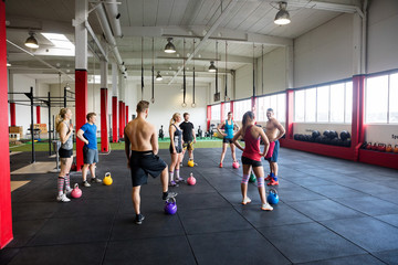 Men And Women With Kettlebells Standing In Gym