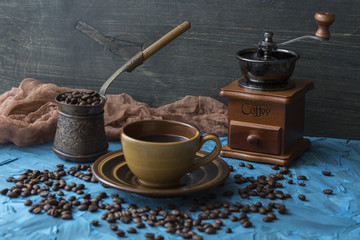 on a blue background a cup of coffee, turka, coffee beans and a coffee mill