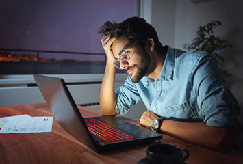 Businessman working on a laptop, overworking, under pressure, tired and sleepy  