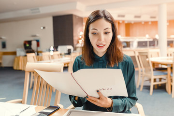 A smiling eastern woman in a restaurant with the menu in hands