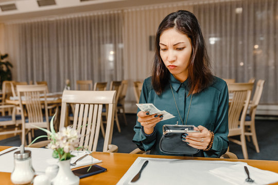 dissatisfied customer woman in the restaurant after dinner gets money out of her wallet to pay the bill, the concept of expensive prices in a cafe