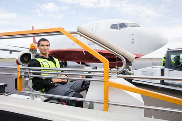 Male Worker Sitting On Luggage Conveyor Truck