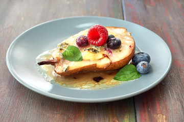 Baked pear with blue cheese and sugar, served withraspberry, blueberry and mint