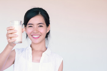 Head Shot portrait of Young Asian woman holding a glass of milk