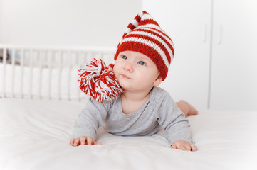 portrait of beautiful infant child in knitted hat lying on bed