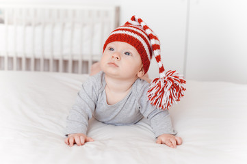 portrait of cute infant child in knitted hat lying on bed