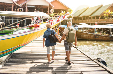 Happy senior couple walking holding hand at Koh Panyi muslim floating village - Active elderly and...