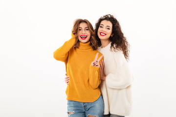 Two smiling girls in sweaters posing together