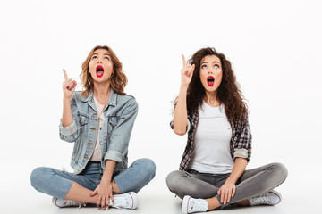 Two surprised girls sitting on he floor together