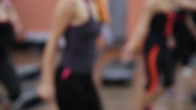 Young healthy sportive women training at gym using step boards. Out of focus video footage.
