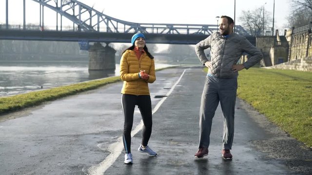 Portrait of happy couple jogging near river in city
