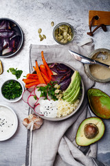 Fresh healthy vegetarian bowl for lunch with baked carrots and red onion, coucous and sliced avocado. Simple and colourful organic food concept. Flat lay with copy space.