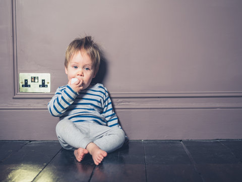 Little boy chewing on electric plug