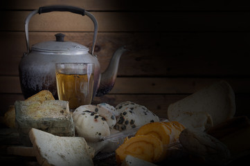 Old Teapot on pile of withered bread and rot on old wooden background and wooden wall which has light splash