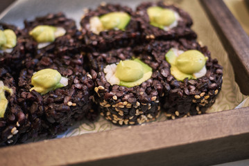 Milan, Italy - December 17, 2017 : Black rice rolls with avocado and shrimps
