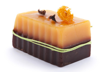 Chocolate orange soap with clove, Illicium, cinnamon and loofah on top isolated on white background