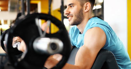 Fototapeta na wymiar Muscular bodybuilder workout in gym doing biceps exercises