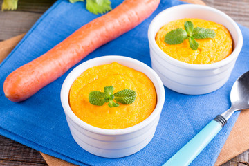 Souffle with carrots and apples in ceramic ramekin on wooden table