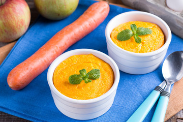 Souffle with carrots and apples in ceramic ramekin on wooden table