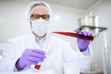 Close up of a doctors hand holding syringe with blood. Analyzing blood in the laboratory.