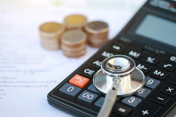 stethoscope and calculator on bills for finance plan or health insurance.
