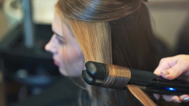 Female hairdresser straightening the hair of a client at a salon