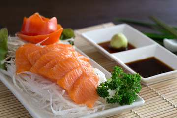Salmon Sashimi and wasabi with black sauce Japanese food in white dish on bamboo mat
