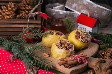 Baked apples stuffed with berries, walnuts and honey on a wooden cutting board.