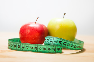 Healthy diet, fitness and weight loss concept. Two apples and a measuring tape on the table.