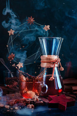 Coffee cup with a dynamic splash and steam with a donut constellation. Hourglass-shaped coffeemaker on a dark background with copy space. Action food photography. Alternative coffee brewing concept