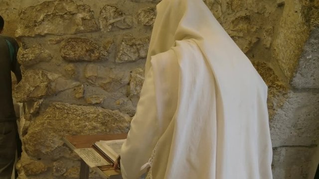 a jewish man in a prayer shawl worships at the wailing wall in jerusalem, israel