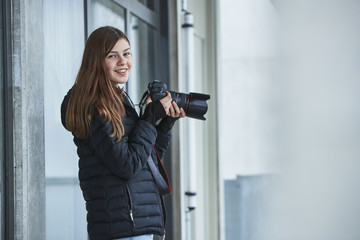 Smiling teenage girl holding digital camera