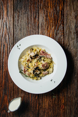 Pasta spaghetti with creamy mushroom sauce in white ceramic plate over old grunge dark table.