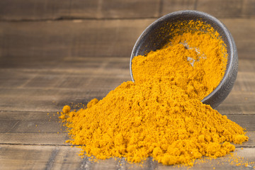 Turmeric in the bowl on wooden background - Cúrcuma