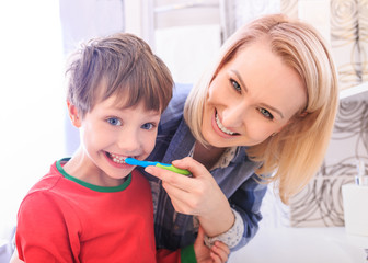 Beautiful happy mother and little son in bathrom brushing teeth together