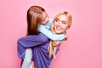 Studio close up portrait, smiling mother carry on back her daughter, they are looking to each...