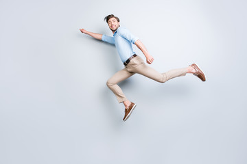 Fototapeta na wymiar Happy, attractive, handsome, young man with bristle jumping in air showing superman pose looking at camera with beaming smile over grey background