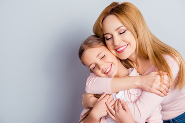 Portrait with copyspace of pretty, lovely mother and daughter embracing over gray background with close eyes, weekend, leisure, happiness, fun, leisure, relatives
