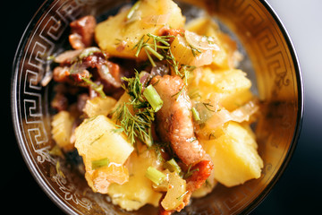 Potatoes with meat and greens in a plate, top view.