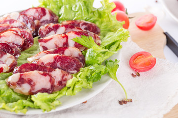 Close-up of cold cuts and vegetables on a plate. Raw pork sausage.