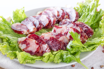 Close-up of cold cuts and vegetables on a plate. Raw pork sausage.